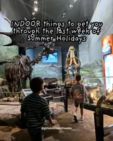 A candid, wide-angle shot of two children walking through a museum exhibit, serving as the cover image for a listicle about indoor activities for the summer holidays.