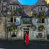 A high-quality, well-composed photograph of a person standing in front of the historic 'The Bridge Tea Rooms' in Bradford-on-Avon. The image effectively captures the charming, traditional stone architecture of the venue, serving as an inviting travel or lifestyle shot.