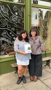 A behind-the-scenes video featuring two women preparing a meal, likely for a book festival event. The video includes segments of them talking, cooking pasta with pesto, and serving dessert to a group of guests.