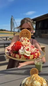 A short, music-led reel featuring a creator visiting a dessert parlour on a farm. The video showcases various waffles, ice cream flavours, and drinks, with the creator sampling the food in an outdoor setting.