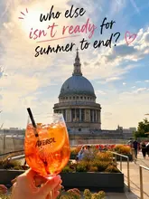 A lifestyle shot featuring an Aperol Spritz held up against the backdrop of St Paul's Cathedral in London, capturing a summer evening atmosphere.