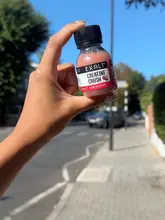 A simple, clear product shot of an Exalt Creatine Crush drink held up against a blurred street background, likely captured during a daily routine.