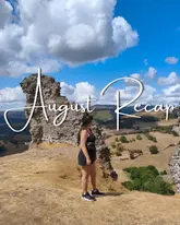 A travel-focused lifestyle shot featuring a person standing on a hill overlooking a valley and ruins, used as a cover for an 'August Recap' video.