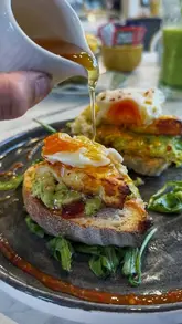 A short, punchy reel showcasing a brunch spot called Ella's of Davenham. The video features a montage of various brunch dishes, including avocado toast with a poached egg, a green smoothie, coffee, and a brownie, alongside shots of the cafe's interior and exterior signage.