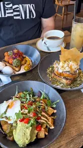 A short video showcasing a brunch spread at a cafe, featuring French toast, egg dishes, avocado toast, and various drinks like coffee and matcha.
