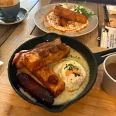 A high-angle, well-composed shot of a brunch table featuring a 'Turbo Poutine' skillet containing crispy hash browns, bacon, sausage, and a fried egg, with a secondary dish visible in the background.