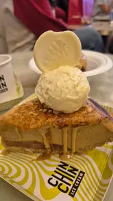 A high-quality, close-up video showcasing the preparation of a banoffee ice cream pie at Chin Chin Ice Cream. The clip features the torching of the caramelised top, the addition of a scoop of tonka bean ice cream, and the placement of a chocolate garnish.