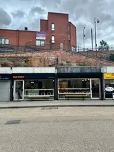 A straightforward, eye-level exterior shot of Bar Caput in Stockport, capturing the shop front on a cloudy day.