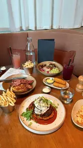 A short montage video showcasing a brunch spread at Caravan King's Cross, featuring close-ups of pancakes, croquettes, buttermilk chicken, and drinks, alongside brief shots of the restaurant interior and the canal-side exterior.