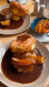 A montage video showcasing a Sunday roast meal at The Stables, Beamish Hall. The video features close-up shots of various roast meats, Yorkshire puddings, sides like cauliflower cheese, and desserts, alongside shots of the venue's interior and exterior.