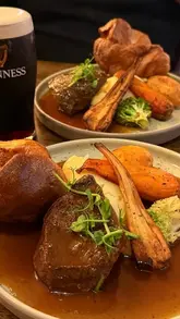 A montage of Sunday roast dinners featuring beef and chicken, served with Yorkshire puddings, roasted vegetables, and gravy, accompanied by pints of Guinness and Harp.