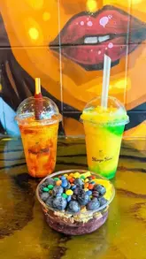 A short, energetic video showcasing Mango Twist, a venue specializing in mango-based drinks, slushies, and acai bowls. The video features quick cuts of the menu, the preparation area, and close-ups of the finished products, including a 'Volcano' slush and an acai bowl topped with fruit and candy.