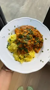 A home cooking tutorial demonstrating how to make a roasted cauliflower and chickpea curry, featuring step-by-step preparation from roasting vegetables to simmering the sauce.