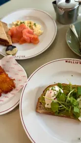 A vlog-style reel showcasing a family stay at Mollie's Motel & Diner, featuring shots of the exterior, interior, various meals including a burger, nachos, and breakfast items, and the creator interacting with their child.