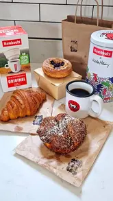 A short, handheld video demonstrating the preparation of a Rombouts single-cup filter coffee at home, paired with various pastries.