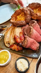A couple visits Corner Grill House in York to review their Sunday sharing roast, showcasing the restaurant's interior, starters, and the main roast platter.