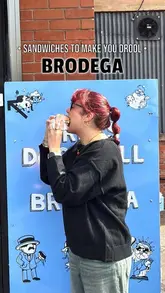 A couple visits a sandwich spot in Manchester called Brodega, highlighting their unique hatch ordering system, the generous portion sizes, and the flavourful combinations of their sandwiches, loaded fries, and tater tots.