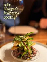 A high-quality, atmospheric close-up shot of a beef tartare dish served at a new restaurant in Glasgow, accompanied by text overlay questioning if it is the city's hottest new opening.