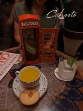 A dimly lit, atmospheric shot of two cocktails and a biscuit served on a lace doily at Cahoots, a 1940s-themed speakeasy in Soho, London.