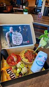 A promotional reel featuring a themed 'Mom's Spaghetti' munch box, showcasing various Italian-inspired street food items including a meatball-stuffed pasta dish, a microphone-shaped croquette, and fried sausage. The video uses close-up shots to highlight the textures and interactive elements of the food, such as injecting basil oil.