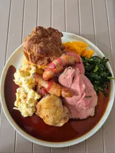 A high-quality, overhead shot of a classic Sunday roast dinner. The lighting is natural and even, highlighting the textures of the meat, the crispness of the Yorkshire pudding, and the glossiness of the gravy. The composition is clean and centered, effectively showcasing the variety of components on the plate without clutter.
