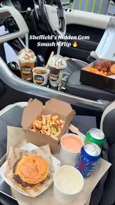 A food haul video showcasing a takeaway meal from Smash N Flip, featuring a smash burger, loaded fries, milkshakes, and banana pudding, filmed primarily inside a car.