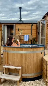 A montage showcasing a countryside staycation venue, highlighting amenities like a hot tub, sauna, cosy bedroom, kitchen, and outdoor BBQ area.