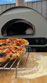 A short, satisfying video demonstrating the use of a portable pizza oven to cook two pizzas simultaneously, focusing on the cooking process and the final result.