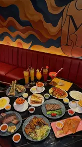 A montage of various meat dishes including steak, lamb chops, brisket, and bone marrow, presented at a modern steakhouse venue. The video focuses on the food presentation and the stylish interior of the restaurant.