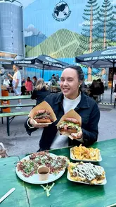 A creator reviews the food from Arditos Kitchen, a pop-up located at Lost and Grounded Brewers in Bristol. The video features close-ups of burgers, birria tacos, and loaded fries, alongside a pint of beer, while the creator shares her enthusiastic thoughts on the menu.