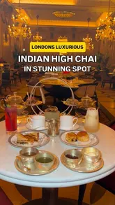 A promotional video showcasing a luxury Indian-inspired afternoon tea service, known as 'High Chai,' at a high-end venue. The video features slow, cinematic pans of the opulent dining room, close-ups of the tea service, and detailed shots of various savory and sweet Indian-inspired delicacies, including samosas, wraps, and tarts.