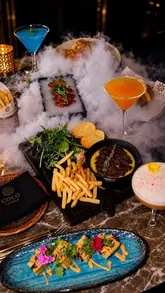 A high-quality promotional montage for Coco Grill & Lounge, featuring a variety of dishes including a signature butter steak, pasta, and desserts, alongside cocktails, set against an upscale, atmospheric backdrop.