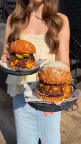A fast-paced listicle video featuring three burger restaurants in London. The creator introduces each spot, shows close-ups of the burgers being cut and eaten, and provides brief commentary on the food quality and specific menu items.
