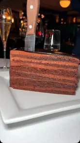 A review of Smith & Wollensky in London, highlighting their famous chocolate cake, rib-eye steak, and sides like mac and cheese and mashed potatoes. The video features the creator enjoying the meal and showcases the restaurant's ambiance and service, including the use of a Coravin wine preservation system.
