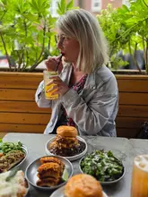 A lifestyle shot featuring a woman enjoying a meal at a restaurant, with a table spread of burgers and sides.