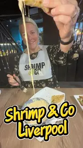 A promotional review video for Shrimp & Co in Liverpool, featuring a variety of seafood dishes, sharing platters, and mocktails. The video includes shots of the restaurant interior, the creator trying the food, and close-ups of the dishes.