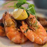 A close-up, macro-style shot of a prawn dish served at The Octagon in Exmouth. The image highlights the texture of the cooked prawns, garnished with fresh herbs and a lemon wedge, focusing on the freshness of the seafood.