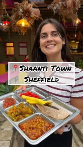 A vlog-style review of Shaanti Town in Sheffield, highlighting its peaceful atmosphere, Indian thali menu, and community-focused ethos. The video features a tour of the venue's indoor and outdoor seating areas, a look at the menu, and shots of the food.
