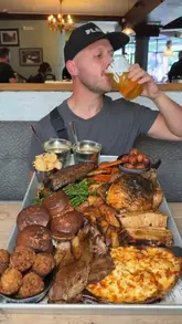 A high-energy food review video featuring a massive smoked meat roast platter at The Drapers Arms in Canterbury, showcasing various meats, sides, and a 'caveman' beef rib.