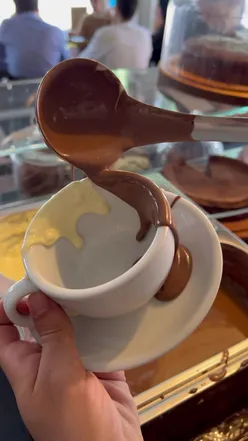 Rich hot chocolate with whipped cream in a cozy London cafรฉ, perfect for chocolate and coffee lovers.