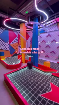 Friends enjoying mini-golf at Birdies with neon lights, sipping cocktails, and savoring delicious burgers in London.