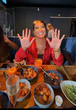 Group enjoying a vibrant bottomless brunch with drinks and food at a trendy London venue, featuring R'n'B vibes.