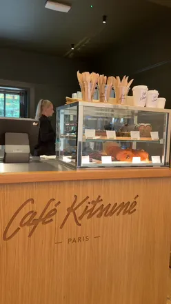 New Cafe Kitsune branch in London with stylish decor and patrons enjoying coffee and pastries.