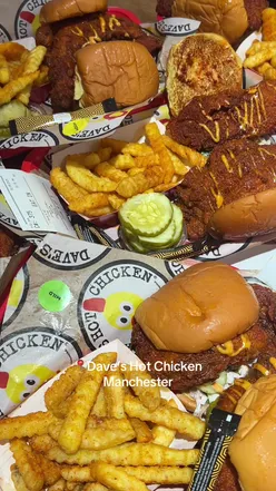 Person enjoying food at Dave's Hot Chicken in Manchester, showcasing delicious spicy chicken dishes.