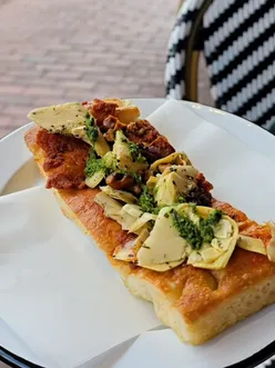 People enjoying fluffy focaccia and delicious bakes at a cozy Brighton eatery, perfect for people watching.
