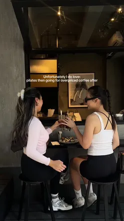 Trendy pilates enthusiasts enjoying coffee at an upscale café, reflecting the 'expensive hobby' culture.