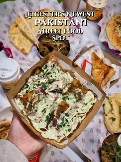 Colorful interior of Naan Staap Leicester with rickshaw and a table of vibrant South Asian dishes and drinks.
