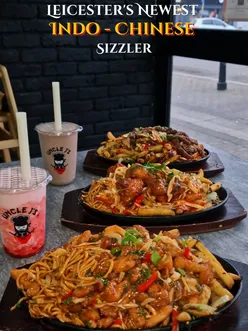Delicious sizzlers with beef, chicken, prawns, and paneer at Uncle J's, served with noodles and chips in Leicester.