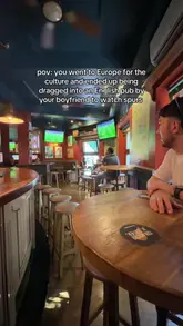 Couple joking about football at a cafe, showcasing a lighthearted moment in travel and sports culture.