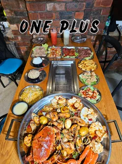 Korean BBQ dining experience at One+ in Manchester, featuring sizzling meats and vibrant dishes.